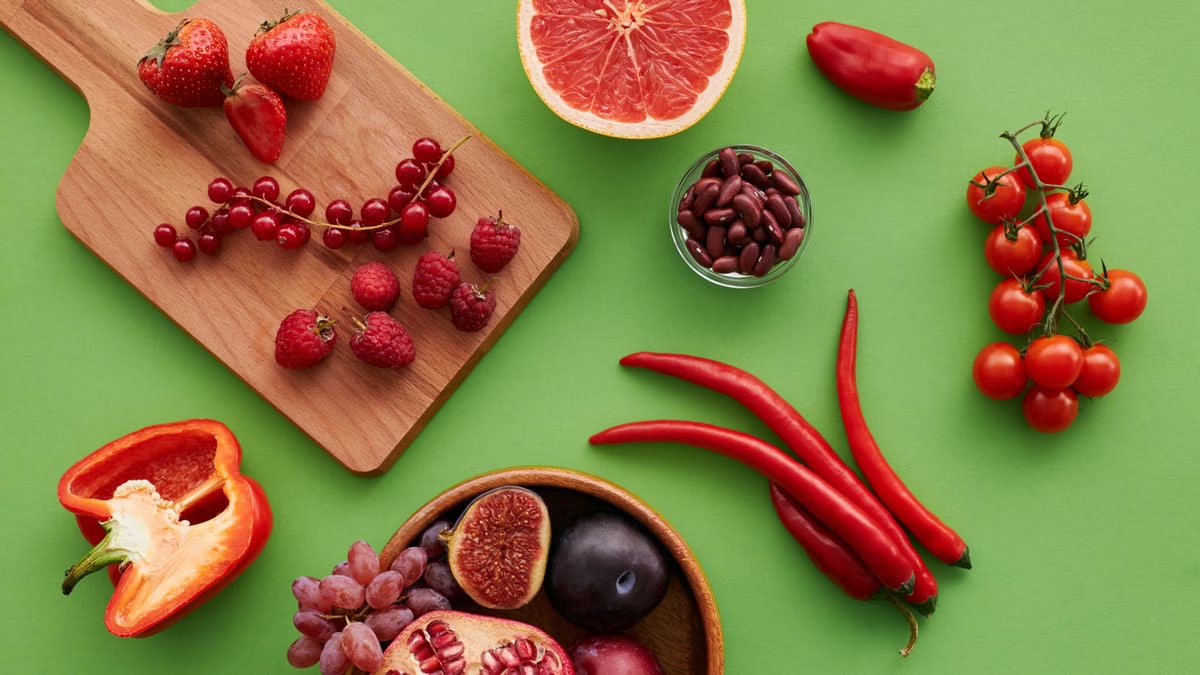 Top view of a vibrant selection of fruits and vegetables on a green background.